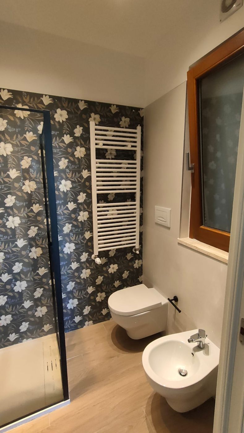 Bagno con wc e bidet sospesi davanti a una parete a fiori