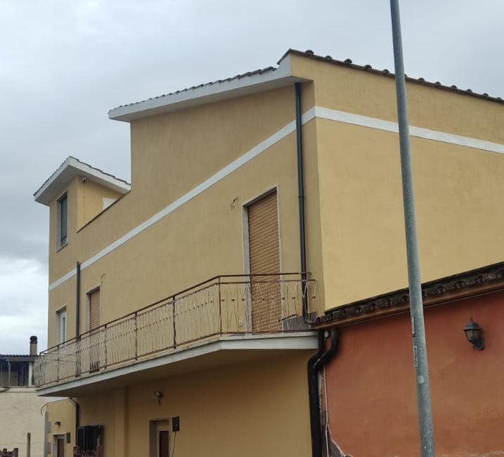Facciata gialla con balcone e fasce bianche dopo il rifacimento
